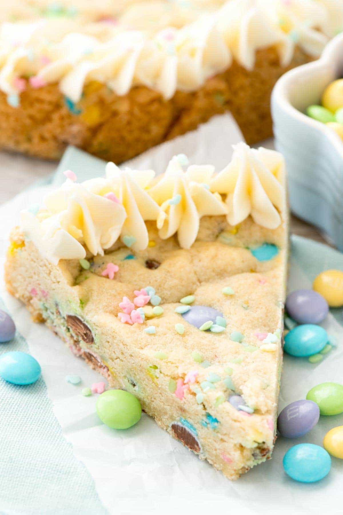 Easter Sugar Cookie Cake - this easy sugar cookie recipe is filled with spring M&Ms and sprinkles and baked in a cake pan. Make an easy frosting and you have the perfect spring cookie cake!